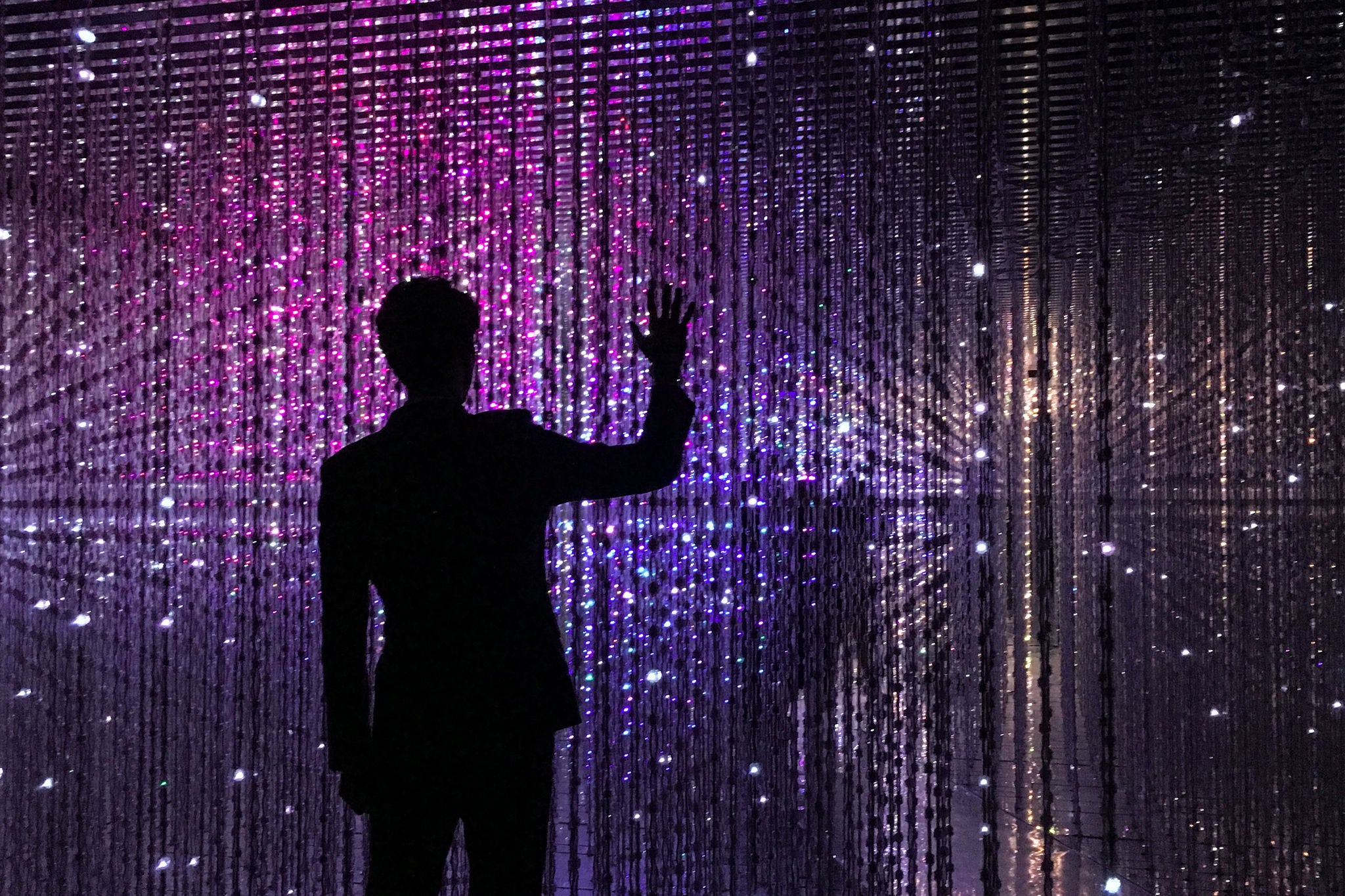 REAR VIEW OF SILHOUETTE MAN STANDING AGAINST ILLUMINATED LIGHTS